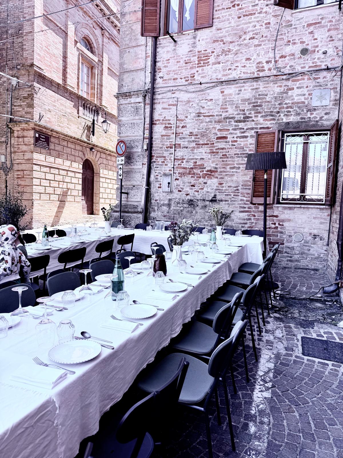 Long table set for dinner in a medieval vicolo in Le Marche